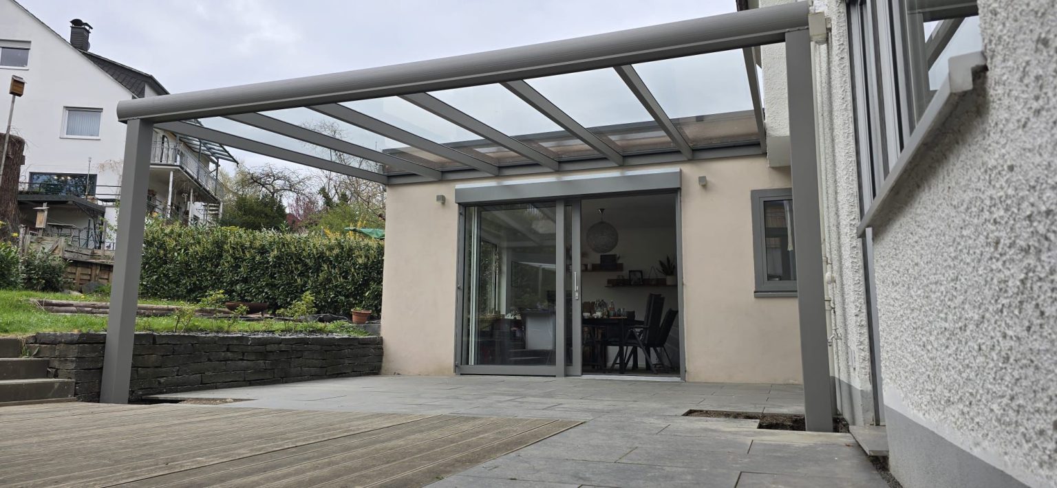 Terrassenüberdachung mit Glasdach an einem hellen Wohnhaus – Projekt von Toku Bauelemente